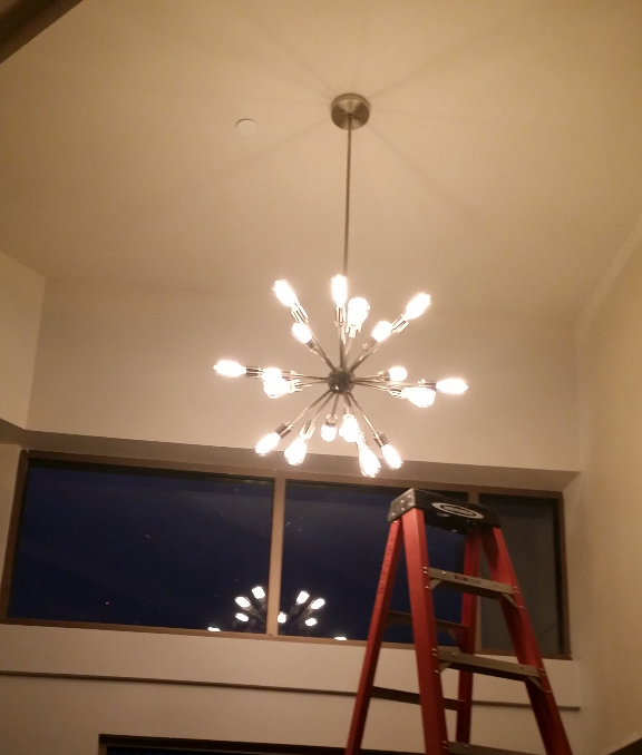 A red ladder is next to a chandelier hanging from the ceiling