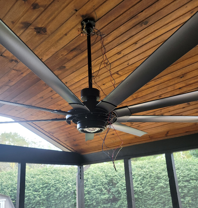 A ceiling fan is hanging from the ceiling of a screened in porch