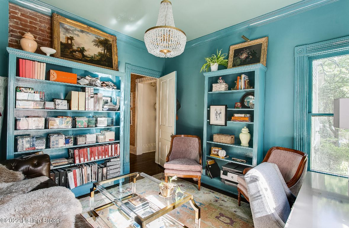 A living room with a couch , chairs , ottoman and a mirror