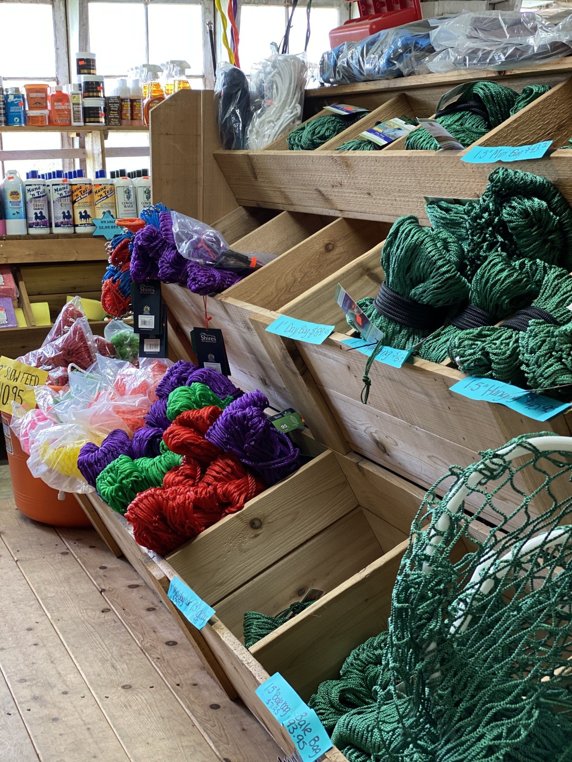 Bins of colorful mesh produce bags and scrubbers displayed in a store aisle.