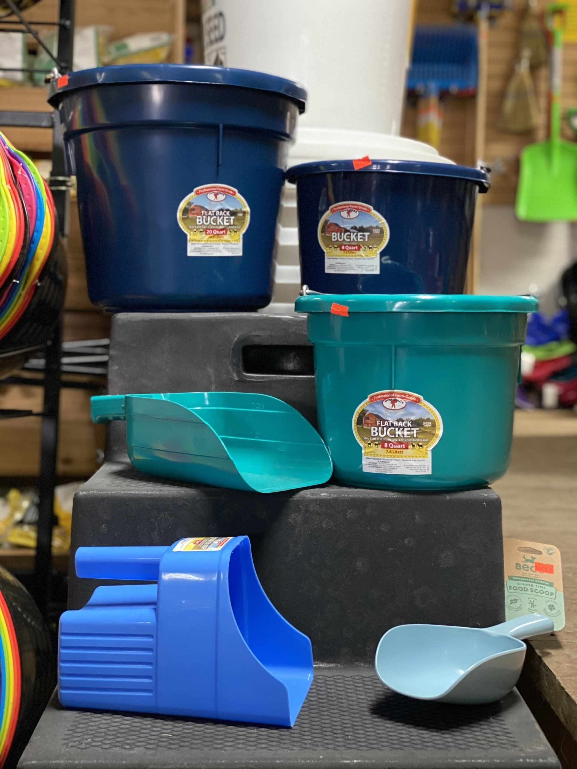 Blue and teal plastic containers and scoops on display in a shop, with woven baskets at left