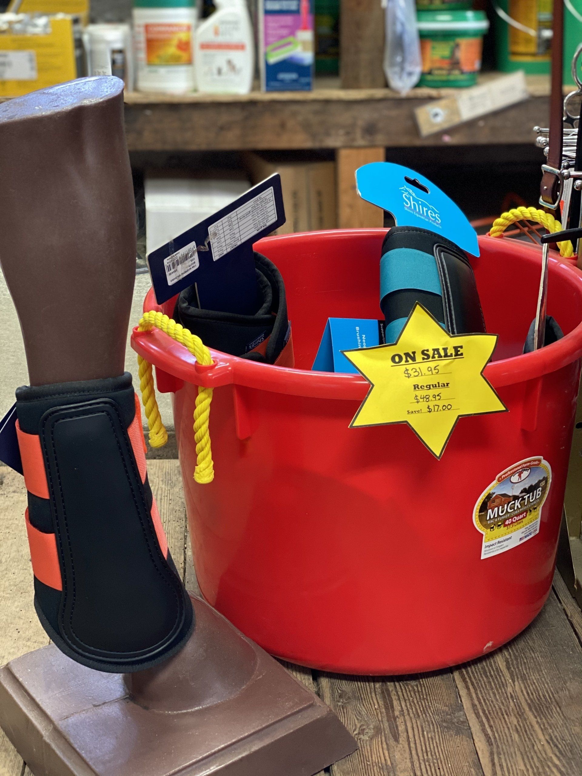 Red bucket with assorted tools and a yellow star tag on a wooden table beside a brown item in a black brace