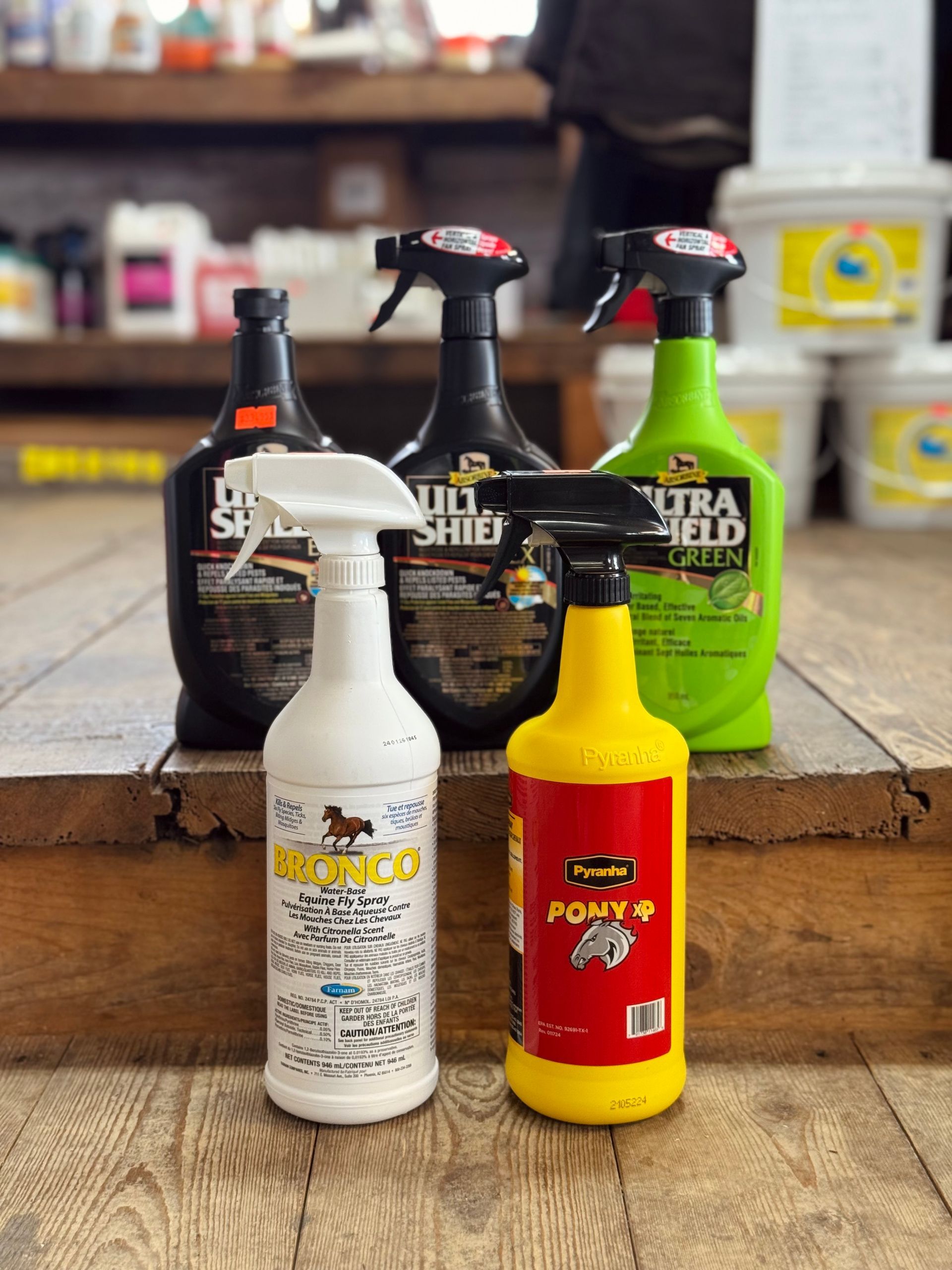 Assorted automotive detailing bottles on a wooden table, including white, red, black, and neon green containers.