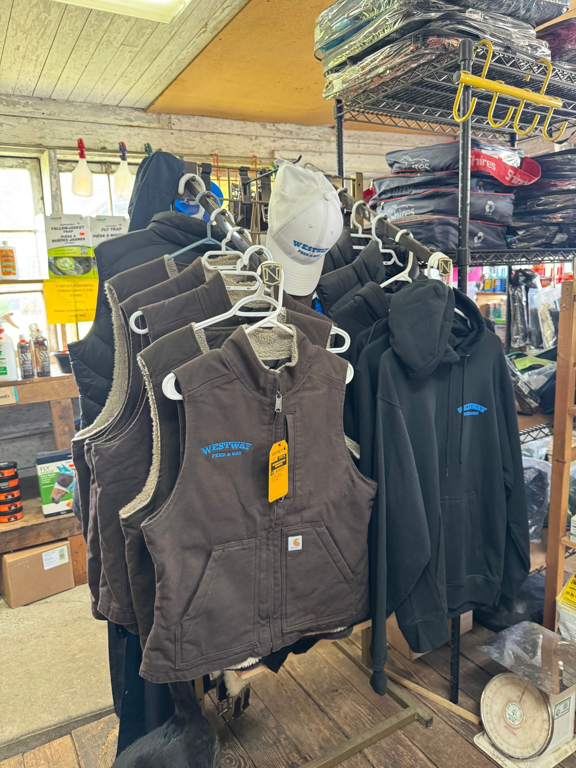 Racks of hooded vests and jackets hanging in a small shop aisle