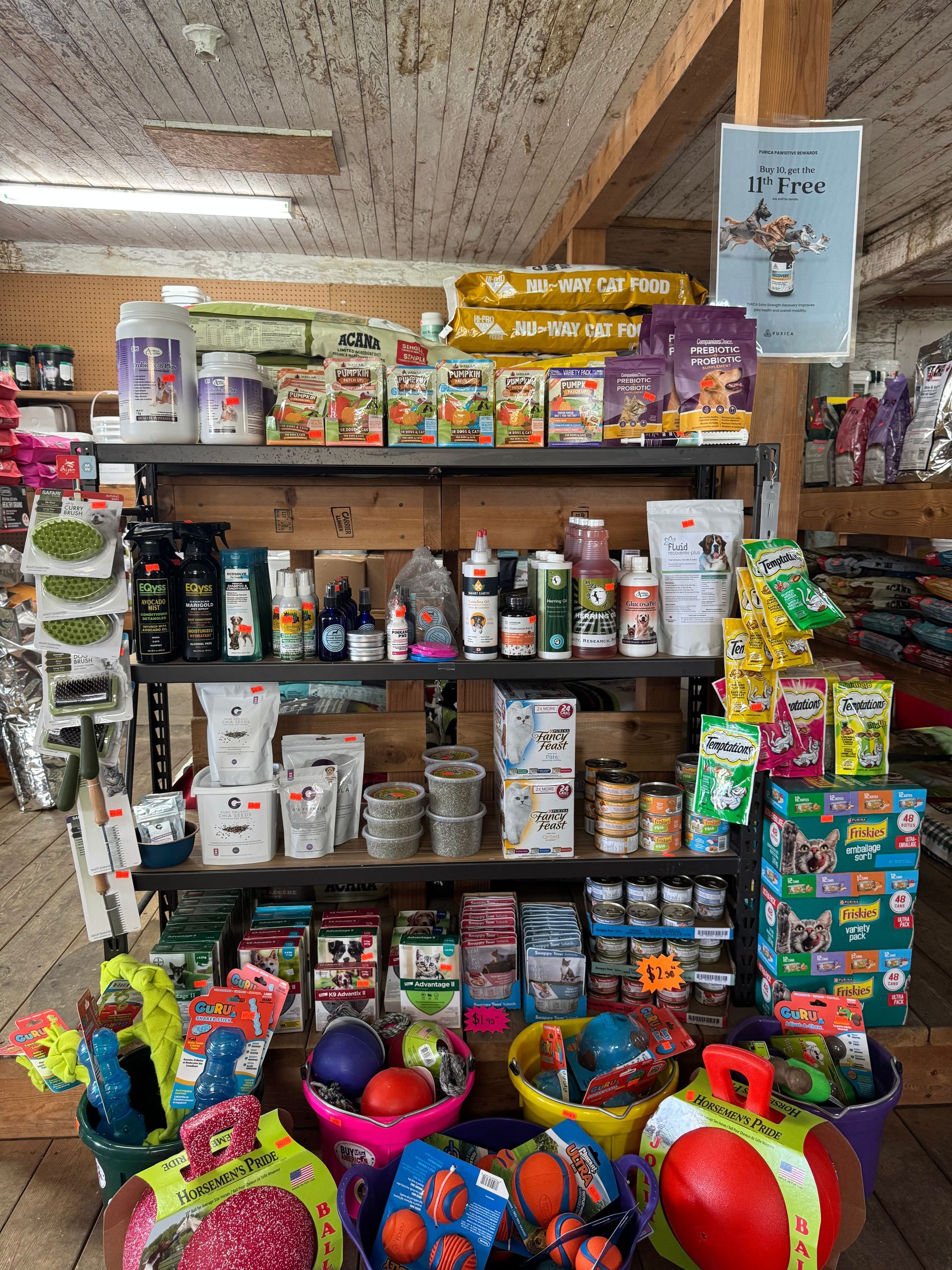 Shelves of assorted snacks and toys in a small convenience shop, with colorful balls and trinkets below