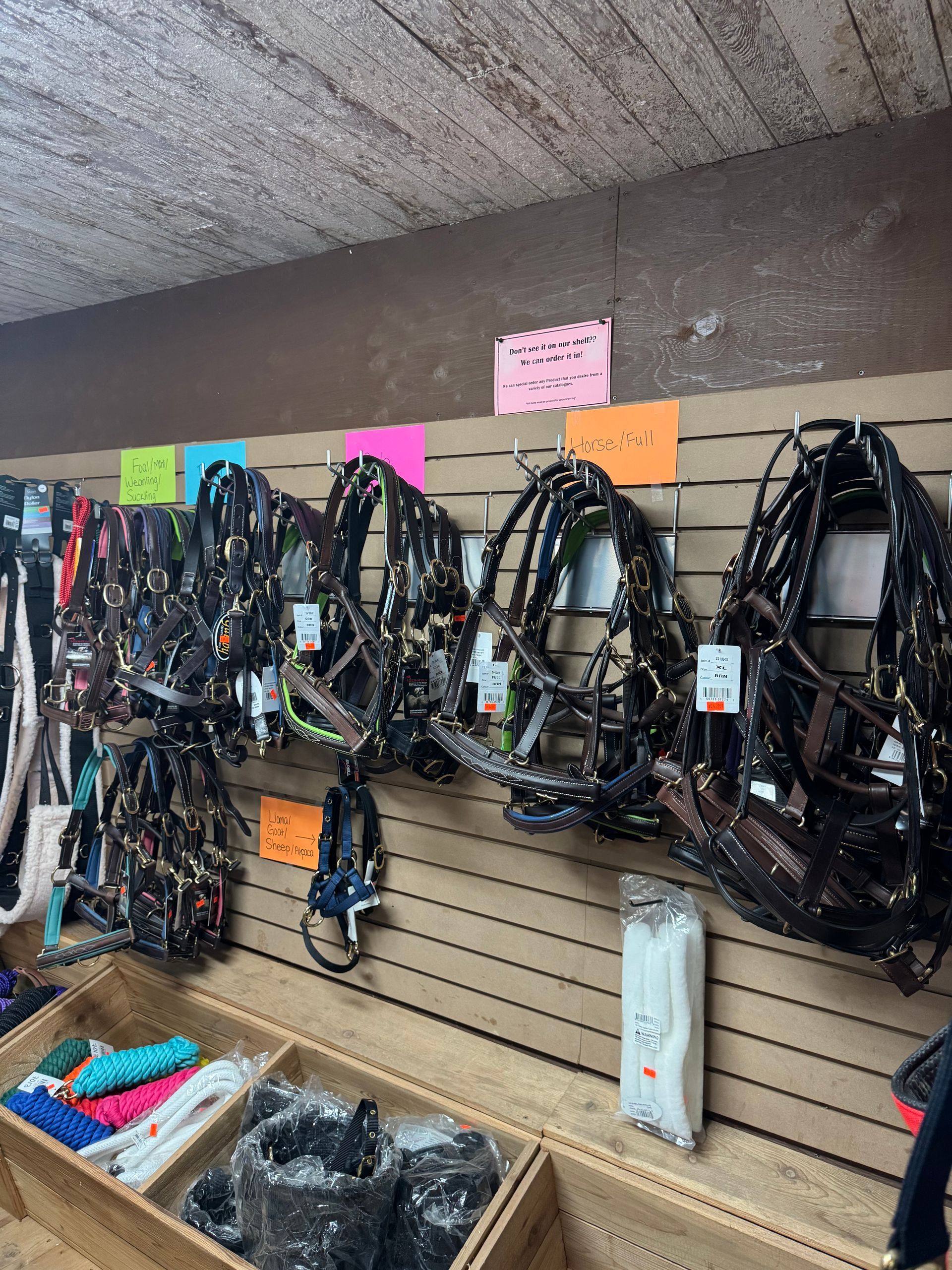 Rows of black harnesses hanging on a slatwall display in a store, with colorful price tags above them