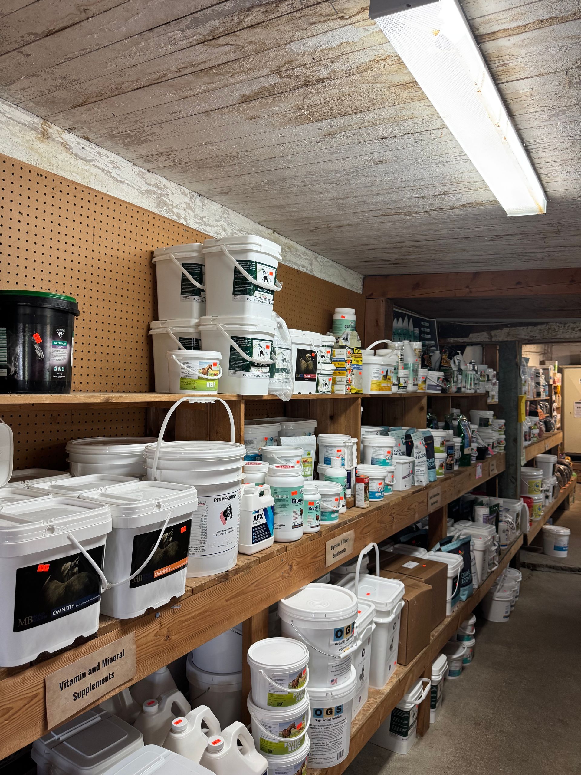 Shelves of assorted paint and supplies in a small store aisle with fluorescent lighting