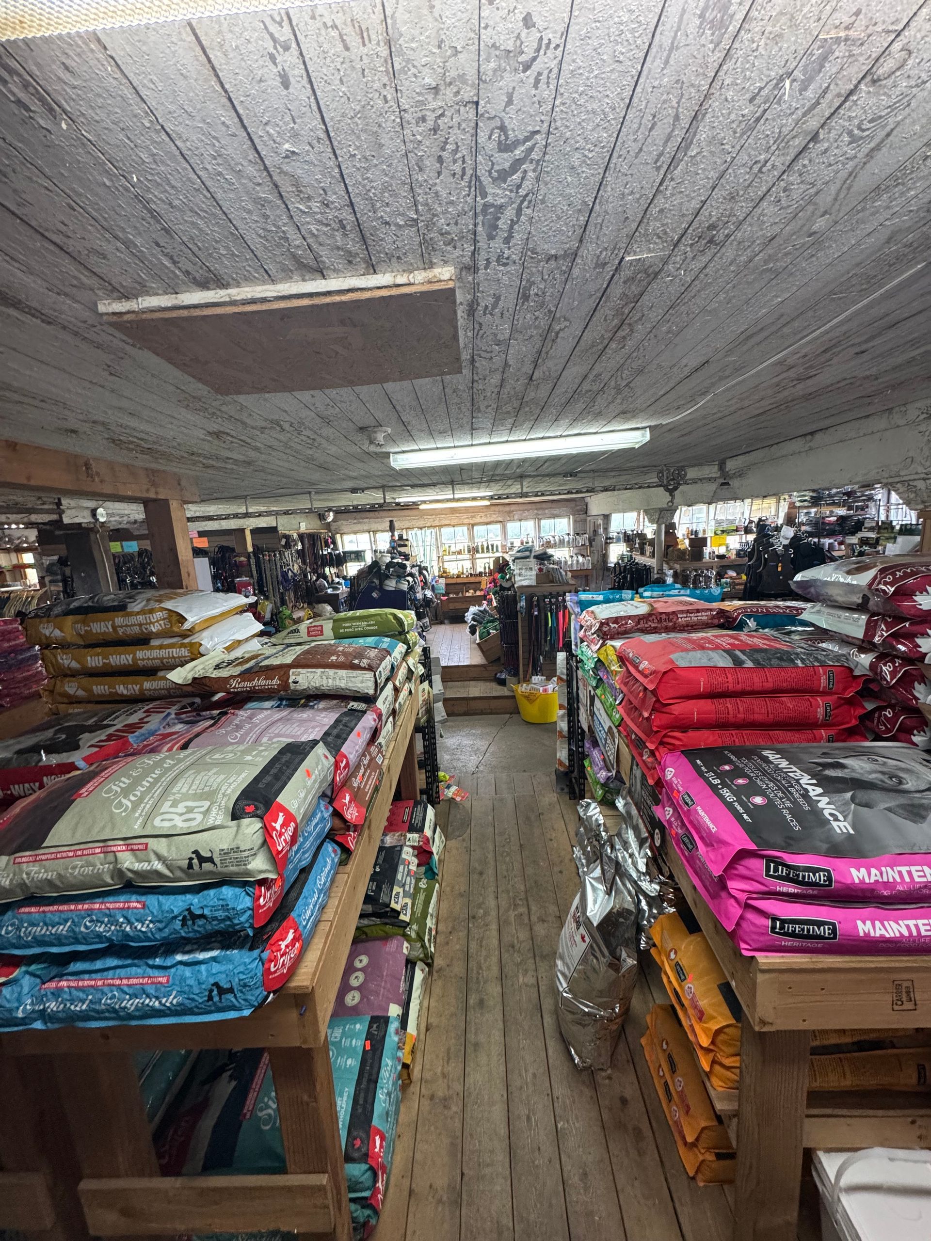 Clothing shop interior with stacks of colorful folded garments on tables and shelves under bright fluorescent lights