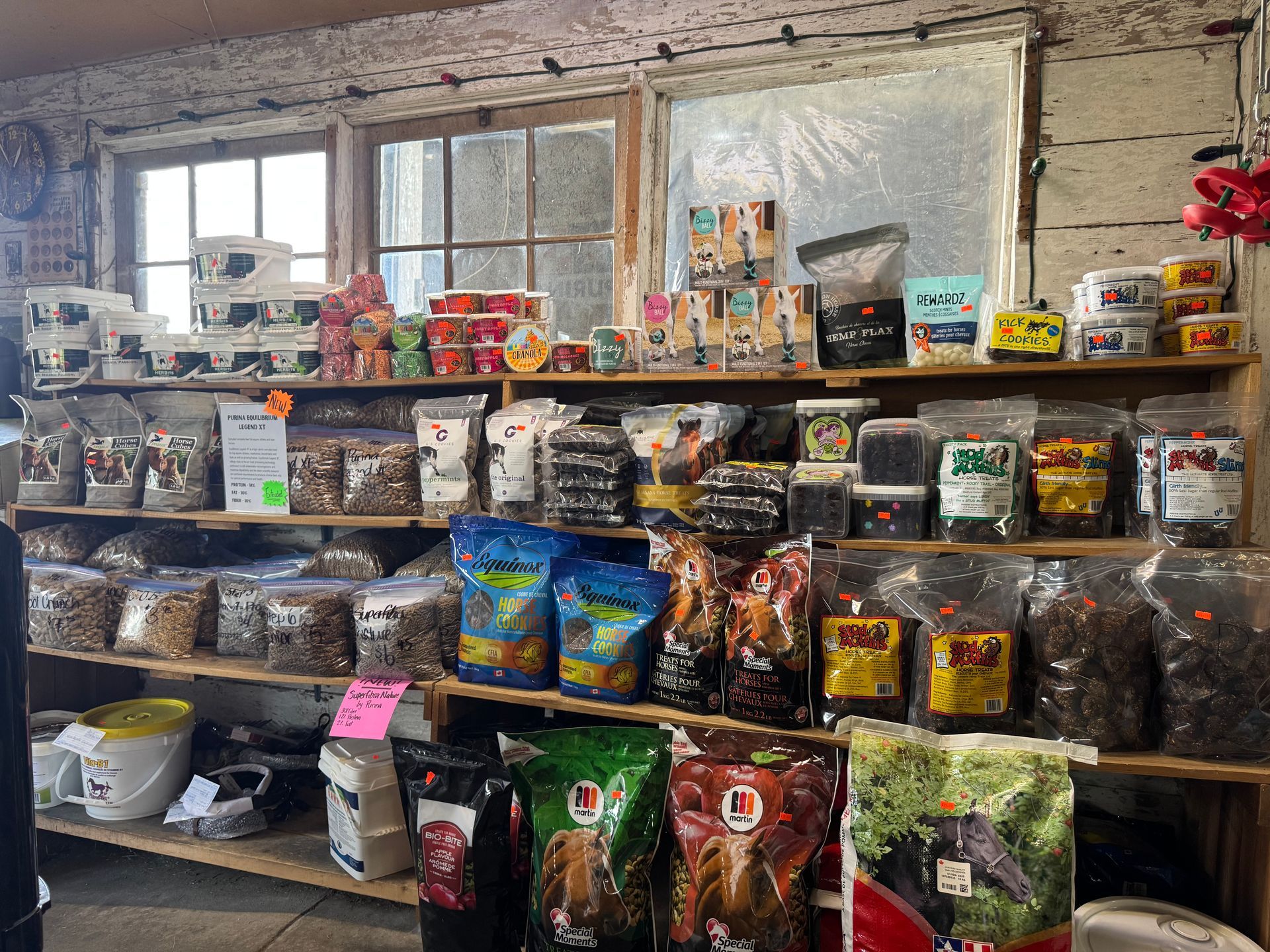 Shelves of assorted packaged goods in a rustic shop or market with large windows and brick walls