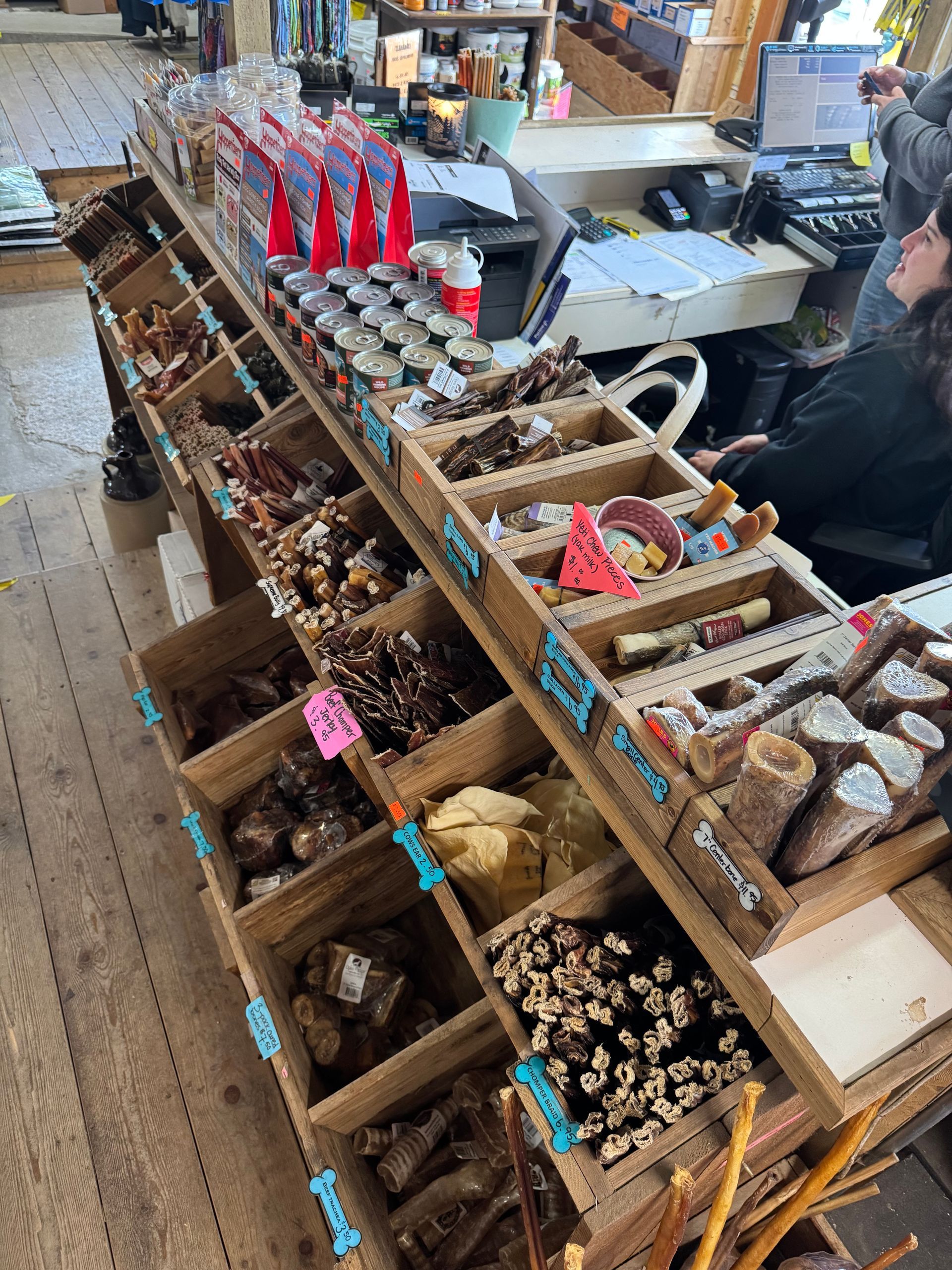 Market stall with wooden bins of assorted dried goods and spices, with a shopper in the background