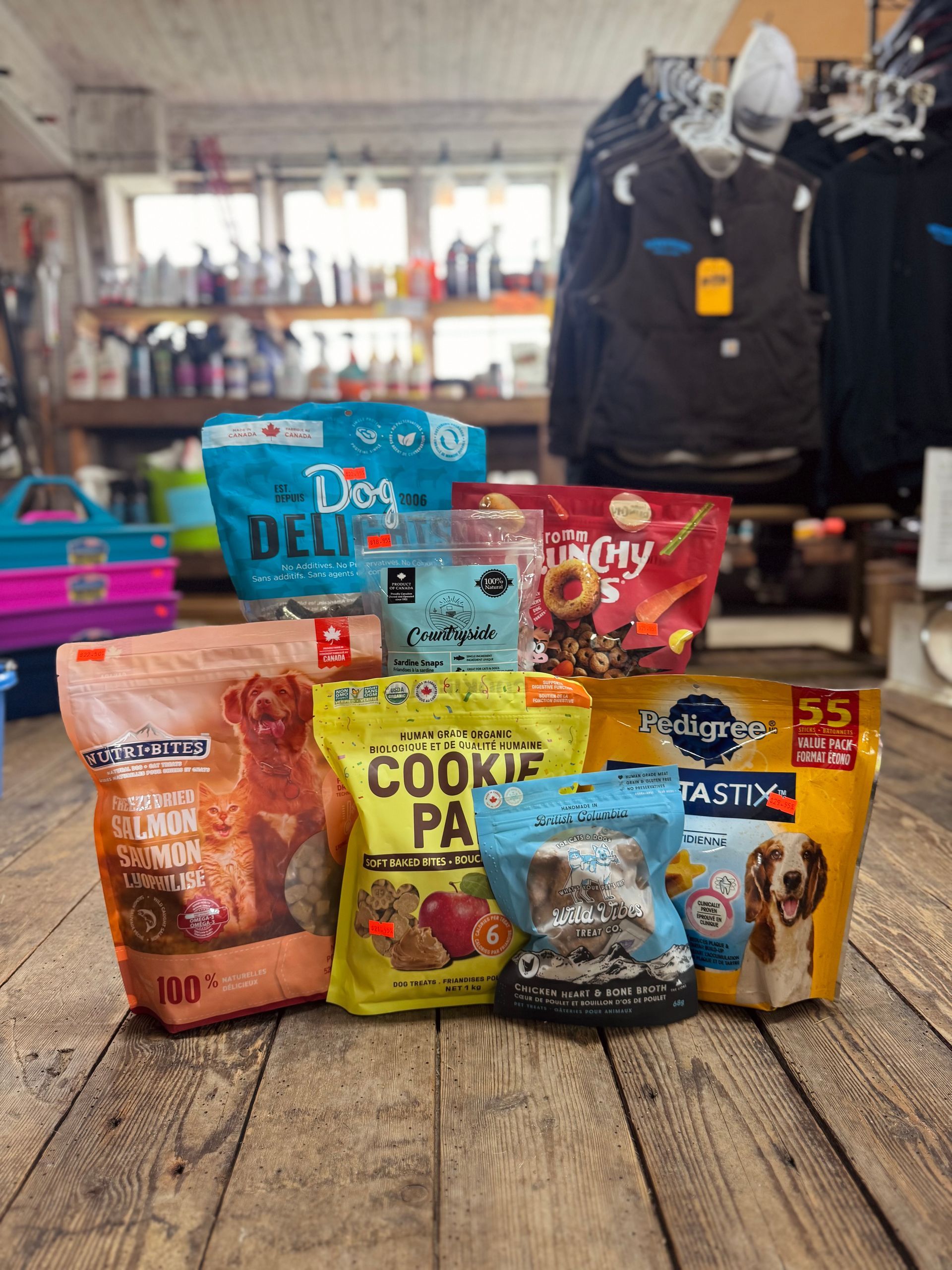 Assorted dog food pouches and cans arranged on a wooden table in a pet store.
