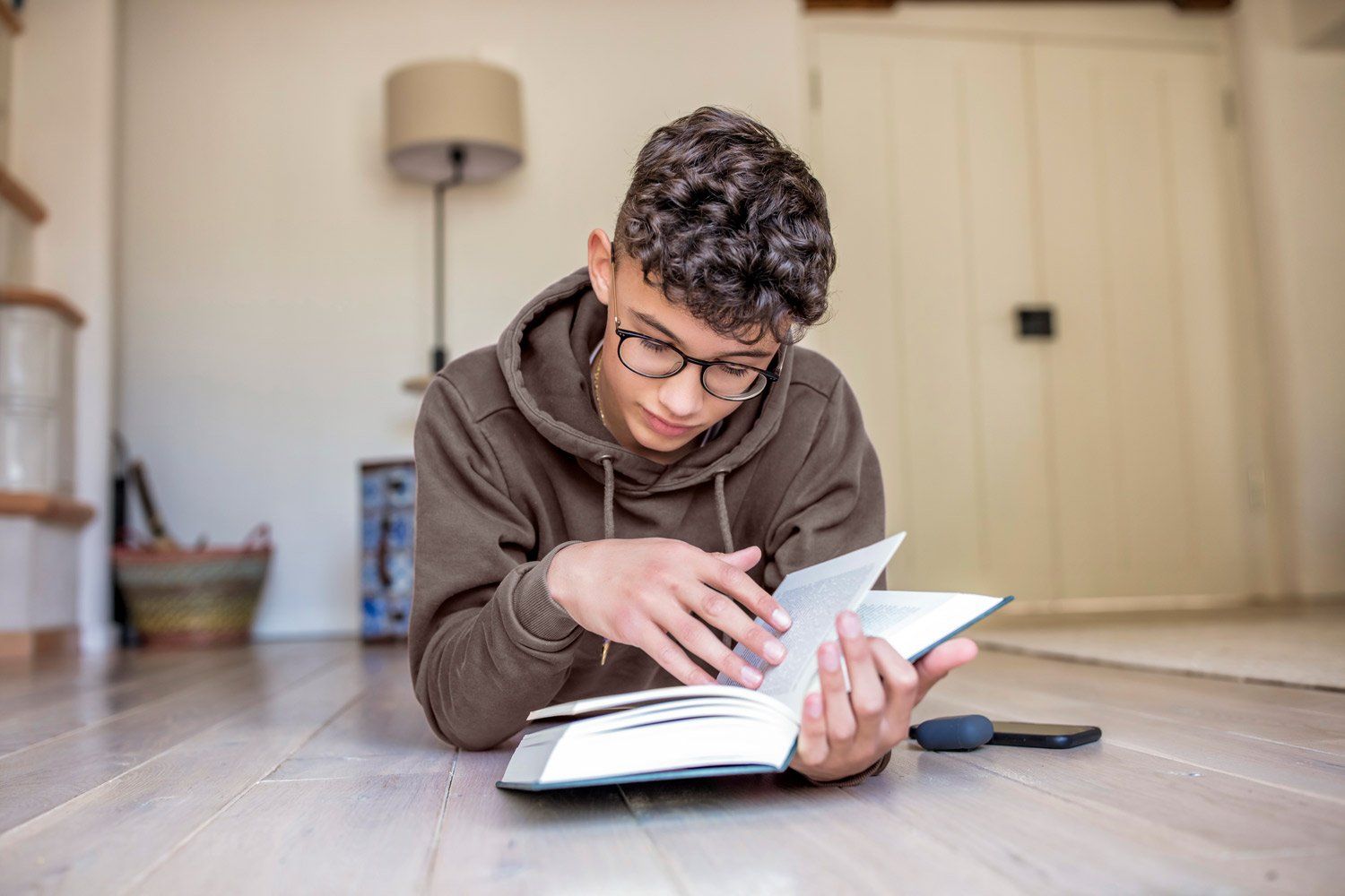 Ein junger Mann liegt auf dem Boden und liest ein Buch.