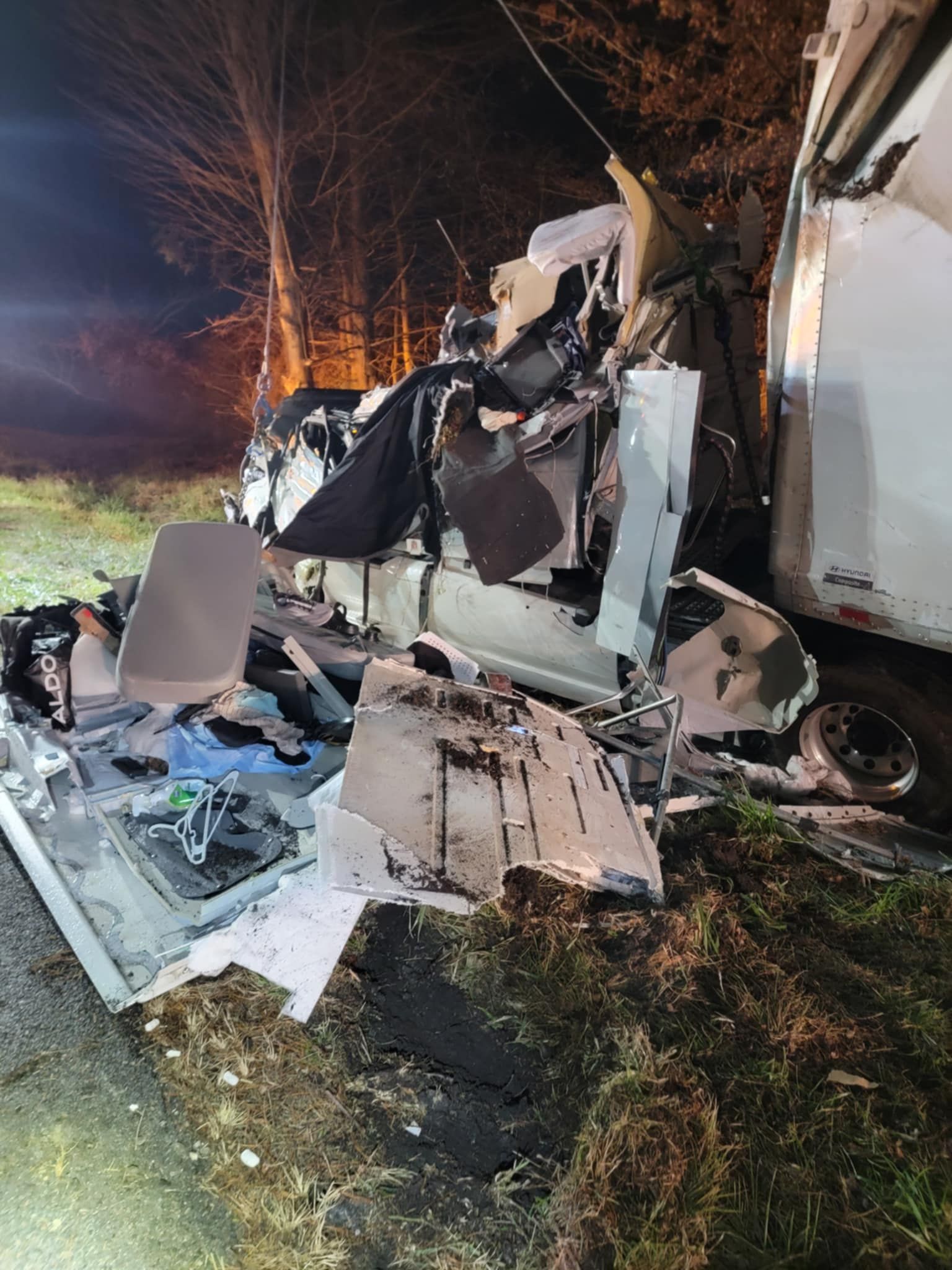 Heavily damaged vehicle wreckage at night; debris scattered on the ground.