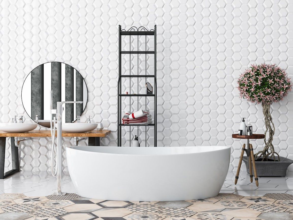 Bagno moderno con vasca freestanding bianca, mensola a scaletta, specchio rotondo e piccolo albero accanto a una panca di legno.