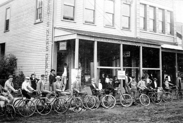 A group of people are riding bicycles in front of a building.