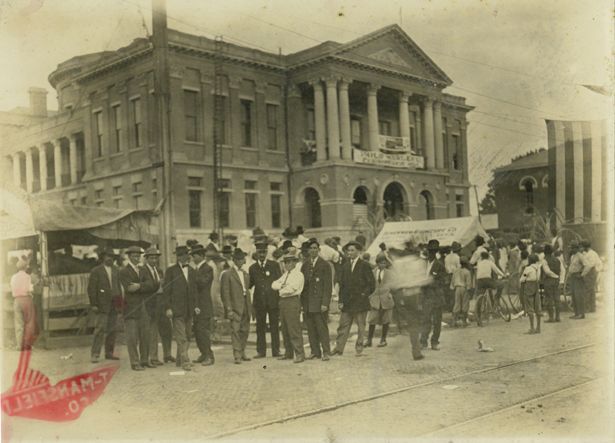 A group of men are standing in front of a large building