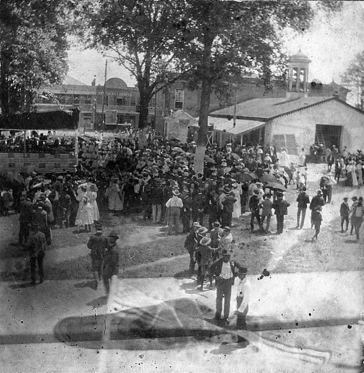 A black and white photo of a crowd of people in front of a building