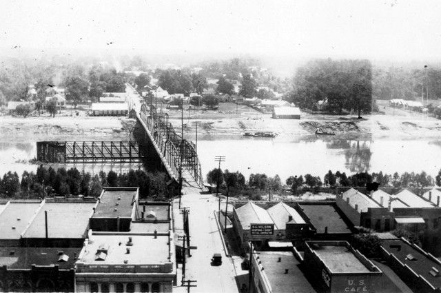 A black and white photo of a bridge over a river