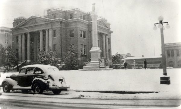 A black and white photo of a car parked in front of a building