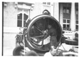 A black and white photo of a man working on a large machine.