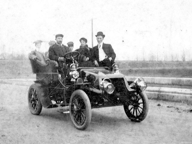 A group of men are sitting in an old car.