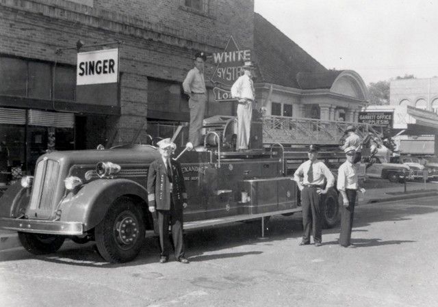 A fire truck is parked in front of a building that says singer
