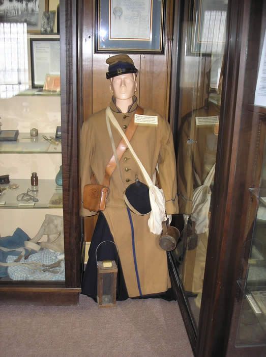 A mannequin in a military uniform is sitting in a glass case