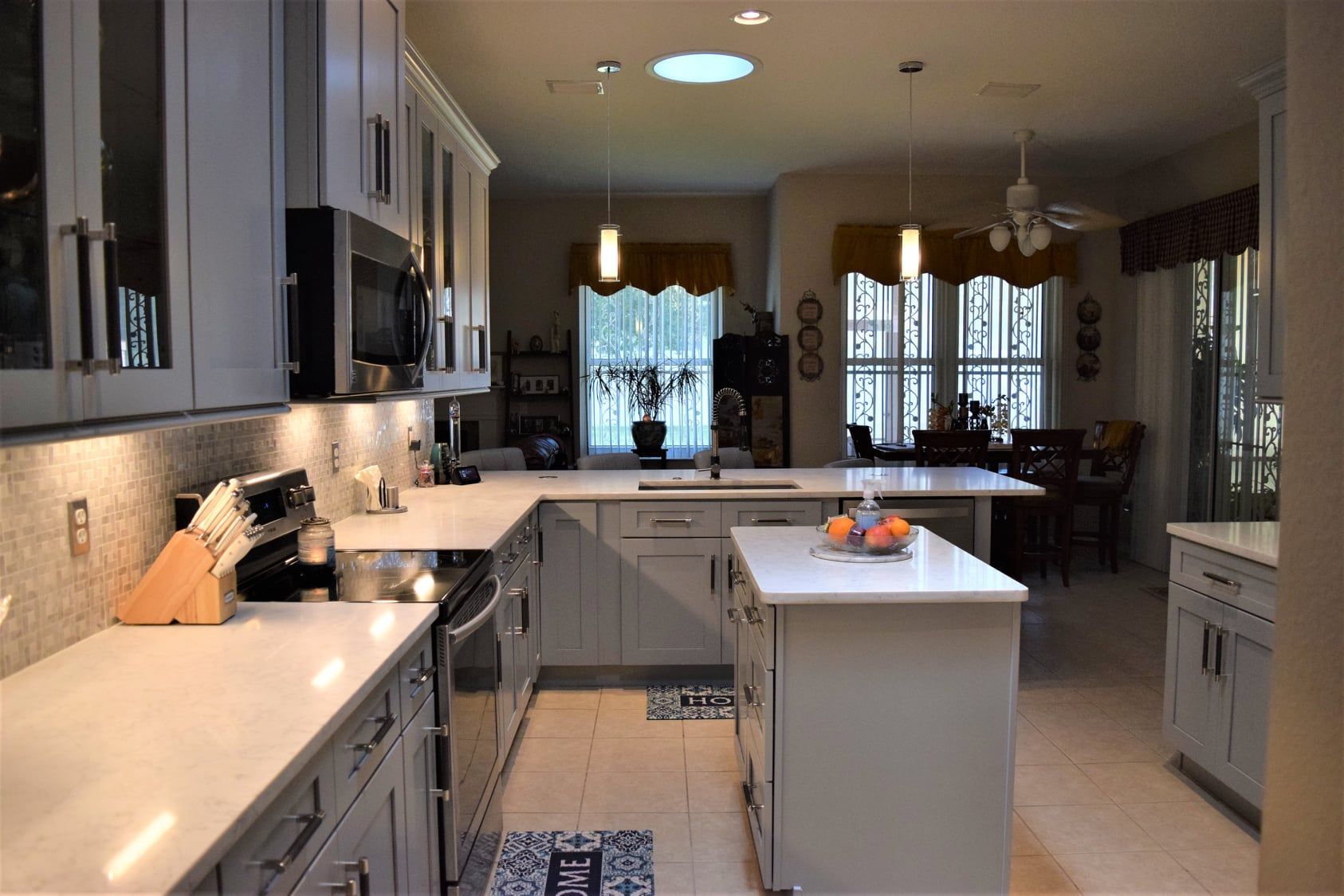 Modern kitchen with white island, gray cabinets, pendant lights, and a fruit bowl on the countertop
