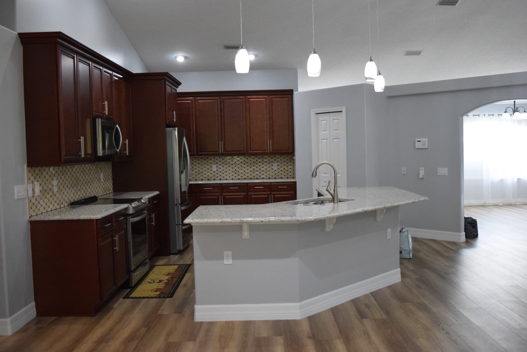 Modern kitchen with dark wood cabinets, white island, and light gray walls with wood flooring