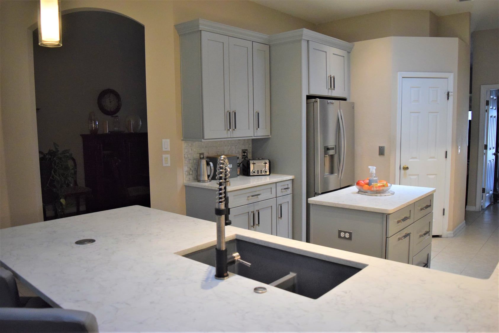 Modern kitchen with white cabinets, island sink, stainless fridge, and pendant lighting