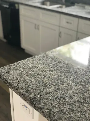 Granite kitchen countertop with white cabinets in the background