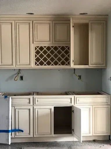 Unfinished kitchen with cream cabinets, open cabinet spaces, and no countertops installed