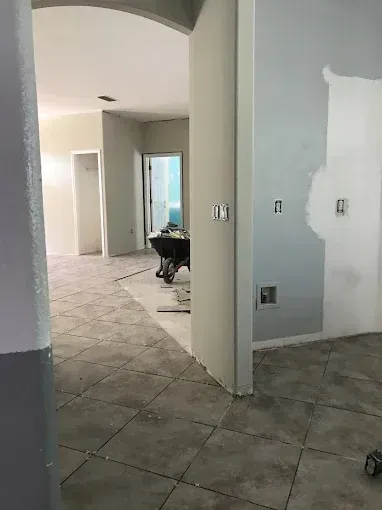 Unfinished interior hallway with gray walls, tiled floor, and open doorways during renovation