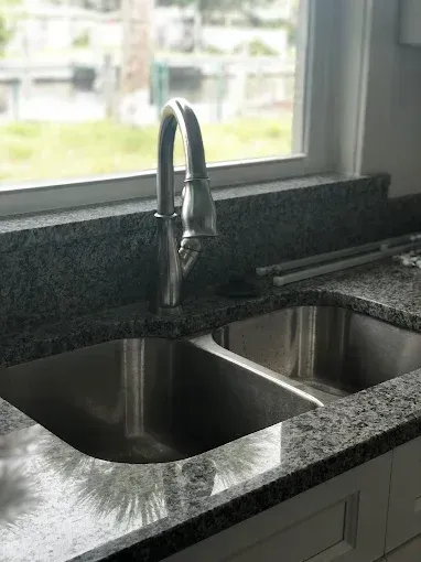 Modern kitchen sink with two stainless steel basins and a chrome faucet by a window