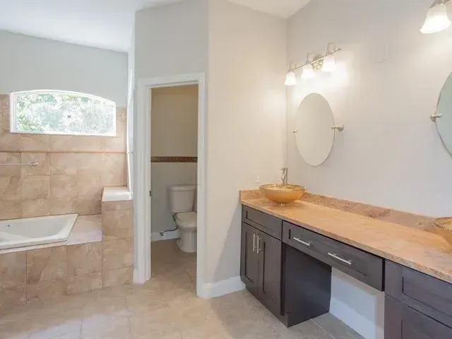 Bright bathroom with vanity, double mirrors, and tiled shower tub area