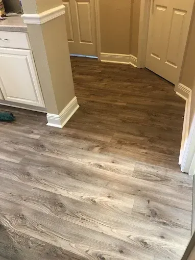 Hallway with wood-look flooring and beige doors leading to a small curved entry area
