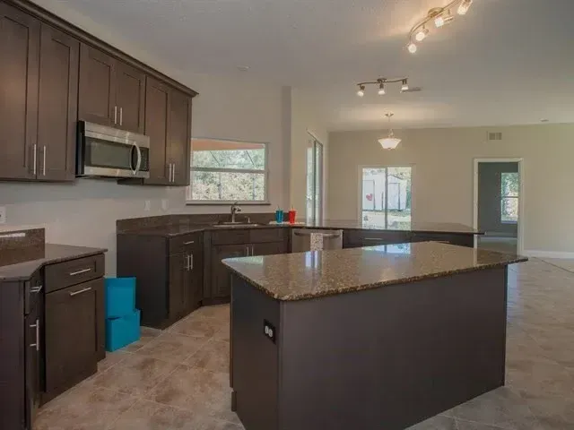 Modern kitchen with dark cabinets, granite island, and stainless steel appliances