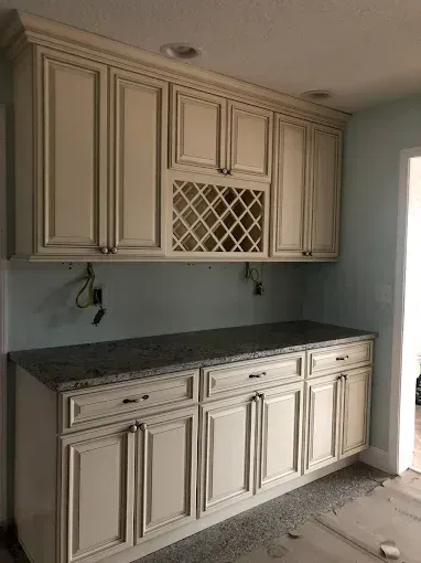 Built-in white cabinets with dark countertop in a small kitchen nook, featuring a wine rack.