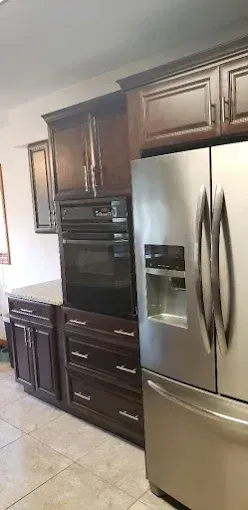 Modern kitchen with dark wood cabinets, built-in oven, and stainless steel French-door refrigerator