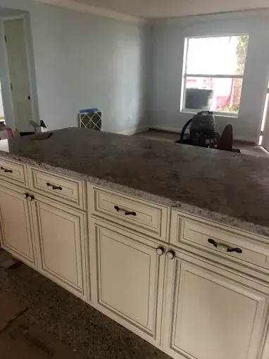 Kitchen with cream cabinets and a large dark countertop in a bright room.