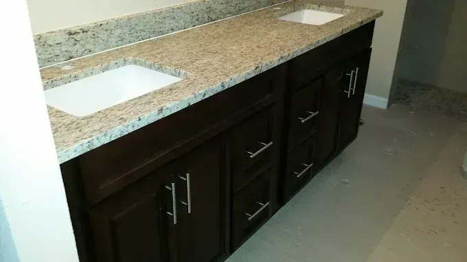 Dark wood bathroom vanity with double sinks and beige granite countertop