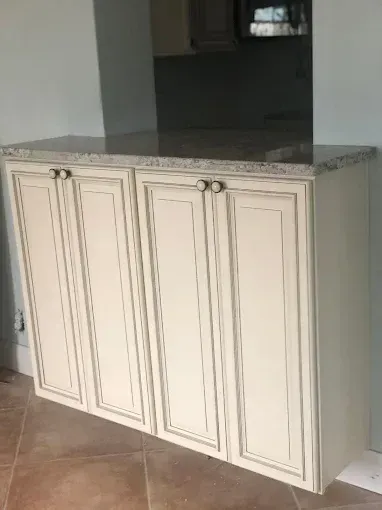 White kitchen cabinet with gray granite countertop in a tiled interior room