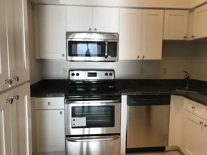 Modern kitchen with stainless steel oven, microwave, dishwasher, and white cabinets.