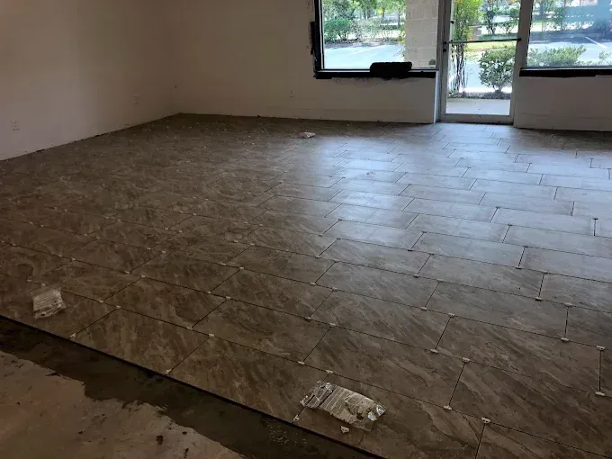 Empty room with dark tile floor, beige walls, and a windowed door opening outside.