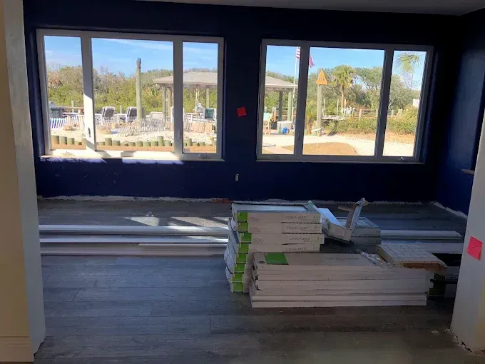 Unfinished room with large windows, stacked construction materials, and bright daylight outside