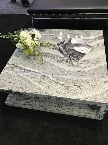 Granite coffee table with a small flower arrangement and a magazine on top