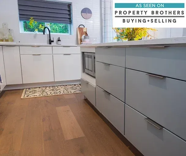 Modern kitchen with white cabinets, wood floor, and a property sign on the wall