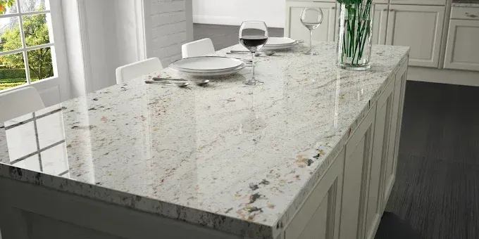 Modern kitchen with a speckled white island countertop, place settings, and a glass vase near a window