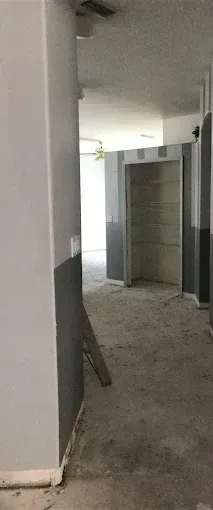 Dusty unfinished hallway with open doorway and concrete walls