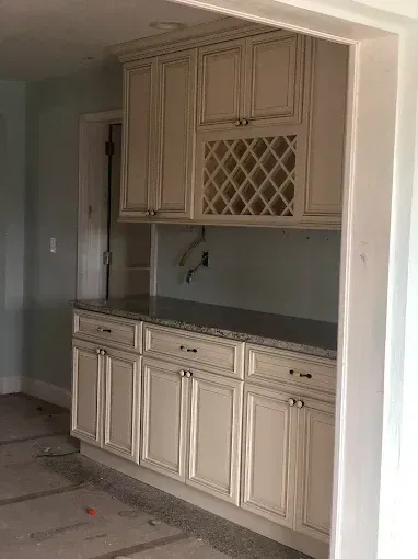Built-in cream cabinets with dark countertop in an unfinished kitchen nook